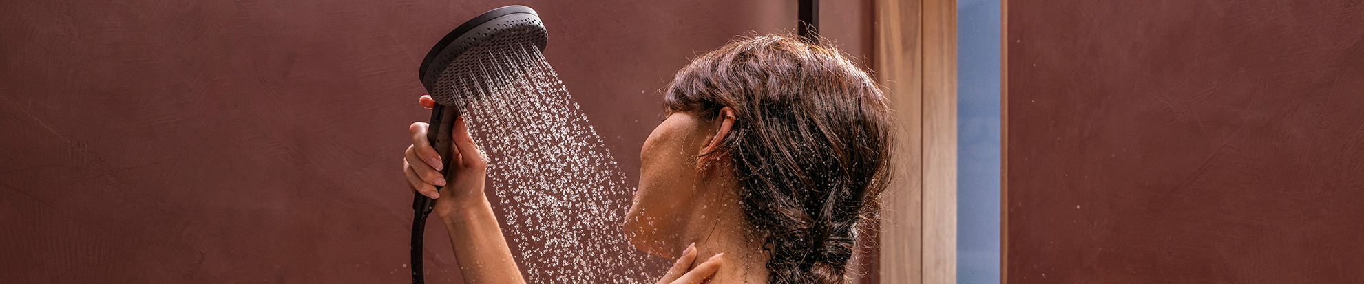 Woman showering with hansgrohe Raindance Alive hand shower.